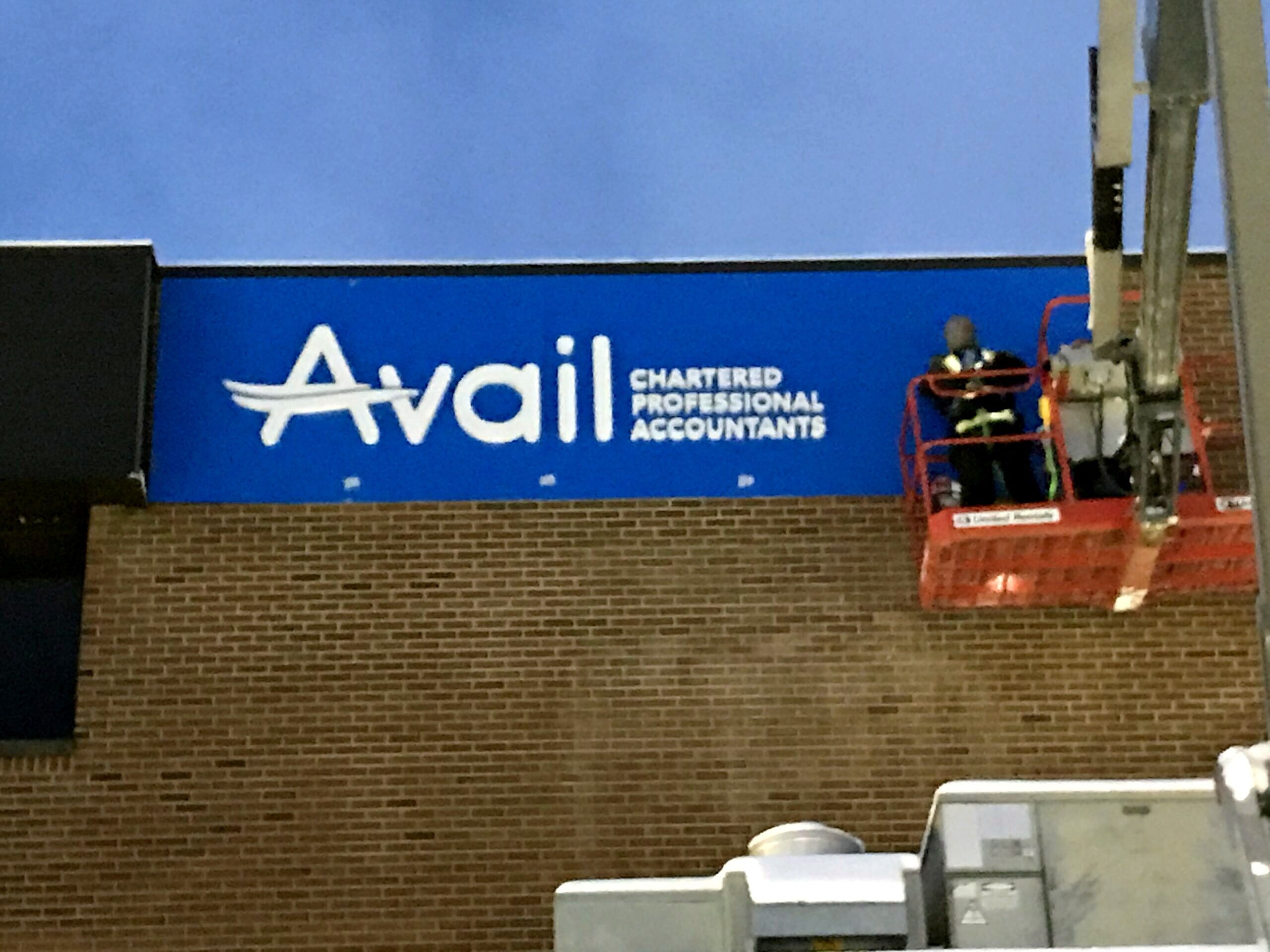 Installer on a boom lift mounting a building sign