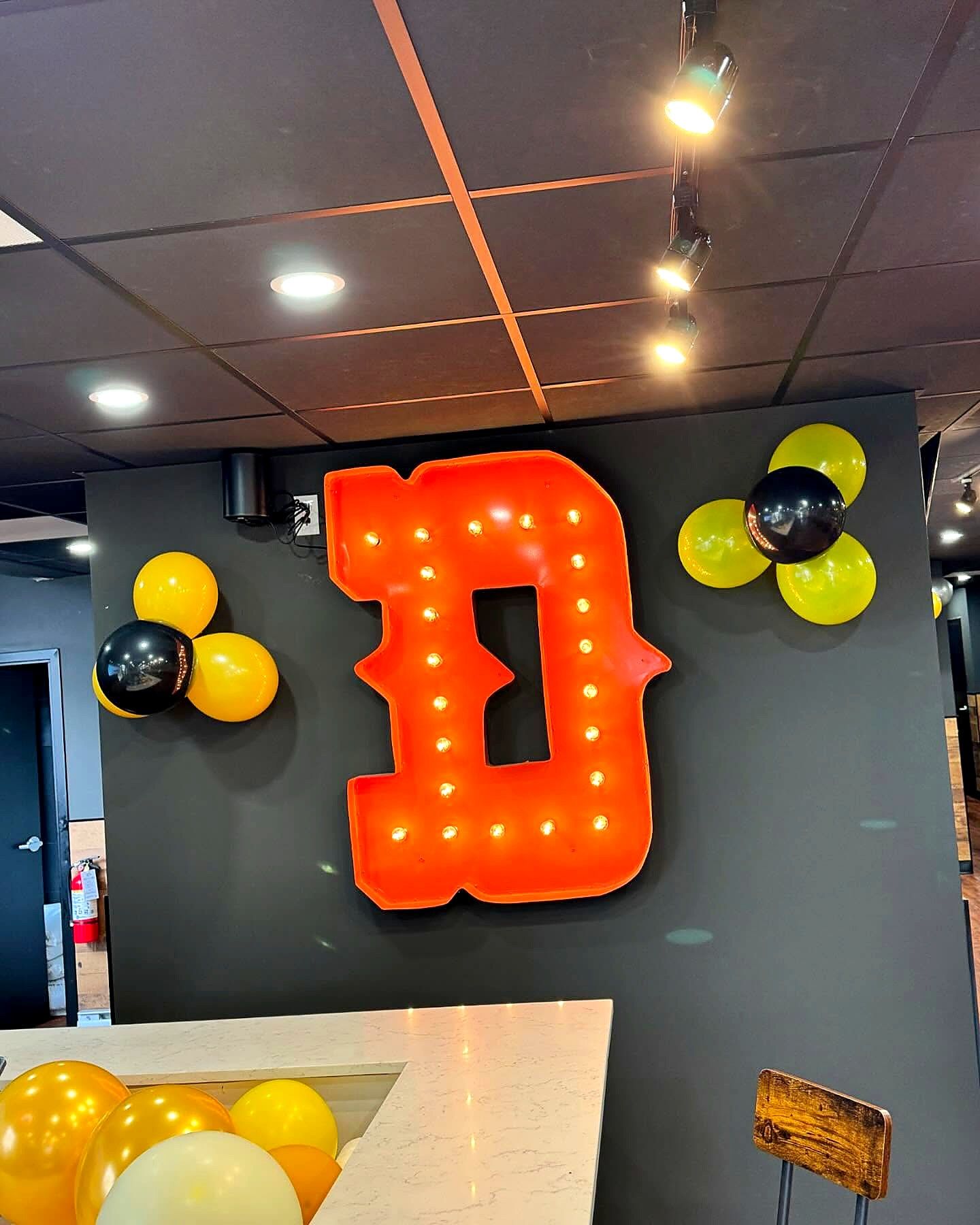 Orange marquee letter D with light bulbs on an interior wall