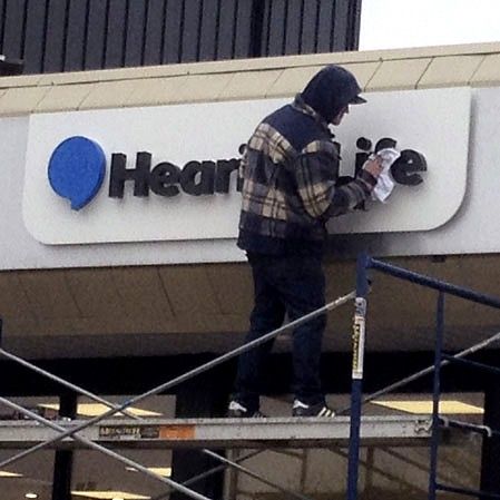 Installer mounting HearingLife letters on a storefront