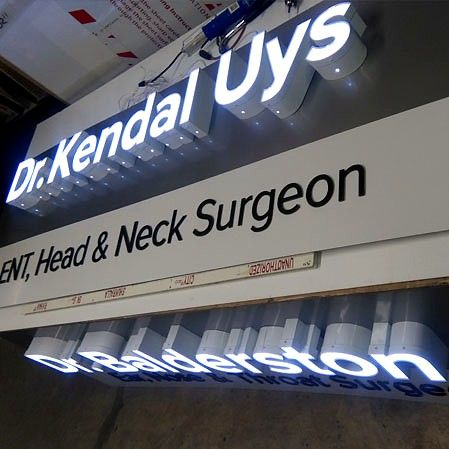 Illuminated channel letters reading Dr. Kendal Uys and Dr. Balderston on a grey fascia